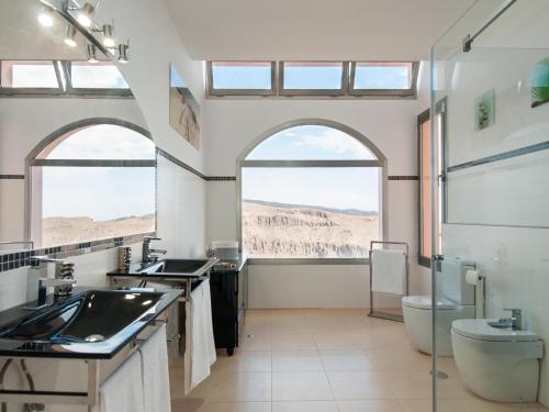 Los PalmitosにあるMajestic Monte Leon by VillaGranCanariaのバスルーム(洗面台2台、トイレ付)、窓2つが備わります。