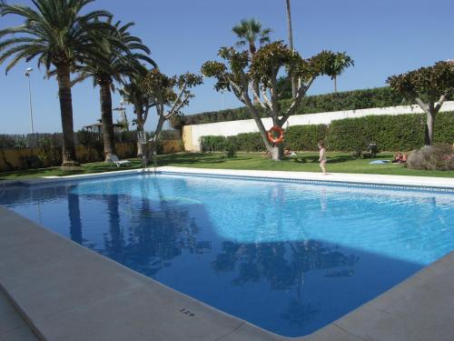 a person walking by a swimming pool with palm trees at Apartamentos Lual Torrecilla in Nerja