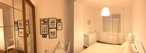 a white room with a bed and a mirror at Casa de Las Flores - Apartamento con jardín privado frente a la Playa de Comillas in Comillas