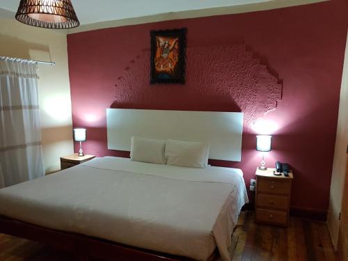 
a bedroom with a bed and a lamp on the wall at Kurumi Hostel in Cusco
