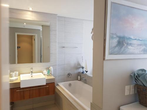 a bathroom with a sink and a tub and a mirror at Harbour Bridge Suite 220 in Cape Town