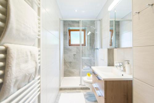 a white bathroom with a shower and a sink at Biohof Maurachgut in Bad Hofgastein