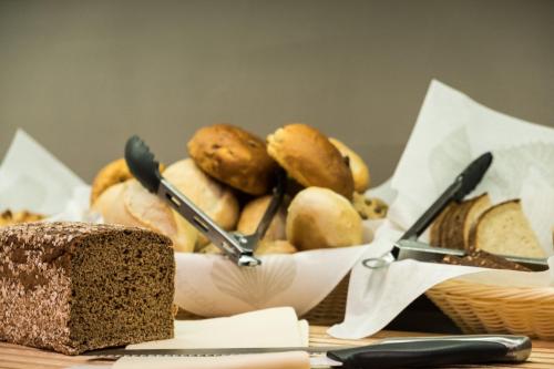 a table topped with a bowl of bread and baskets of bread at Das 53°Hotel in Bad Zwischenahn
