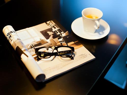 a book and glasses and a cup of coffee on a table at Apartamenty Modern Gdynia in Gdynia