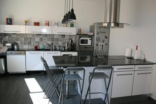 eine Küche mit weißen Schränken und einer Theke mit Stühlen in der Unterkunft Casa Oliva -situé au 2ème étage sans ascenseur in Perpignan