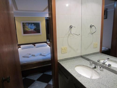 a bathroom with a bed and a sink and a mirror at Hotel Copamar in Rio de Janeiro