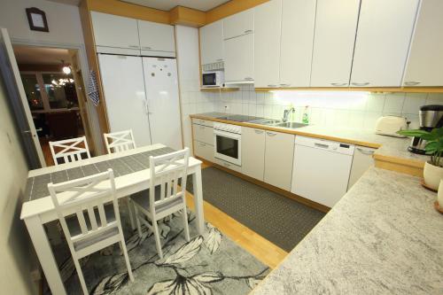 ロヴァニエミにあるミシェル センター アパートメントの白いキャビネット、テーブルと椅子付きのキッチンが備わります。