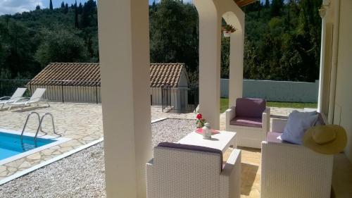 a patio with chairs and a table and a pool at Villa Fedrita in Acharavi