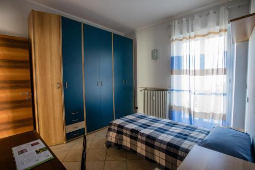 ピネローロにあるTerrazza di Pineroloのベッドルーム1室(ベッド1台、青いキャビネット、窓付)