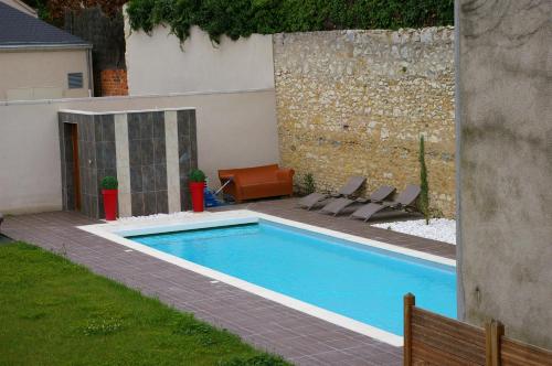 einen Pool in einem Garten mit Stühlen neben einem Gebäude in der Unterkunft Logis Hôtel Le Cheval Noir in Argenton-sur-Creuse