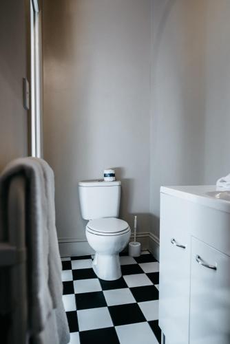 a bathroom with a toilet and a black and white checkered floor at The Grange B&B in Christchurch