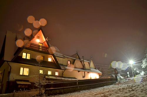 a house with lights on in the snow at night at Gościniec Odsapka in Murzasichle