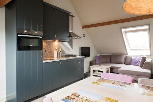 a kitchen with dark blue cabinets and a living room at De Willigen Logies in Vreeland