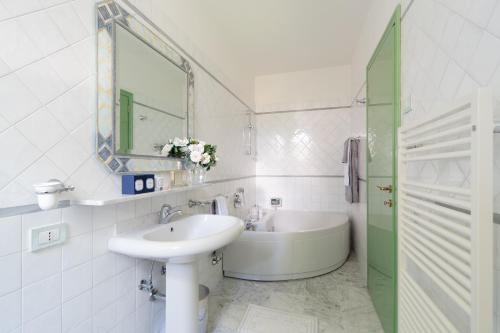 a white bathroom with a sink and a tub at Forte Inn in Forte dei Marmi
