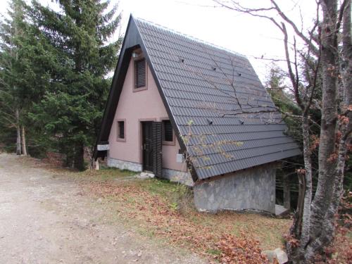 a pink house with a black roof next to a road at Holiday Home Kragovic in Kopaonik