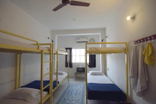 a room with two bunk beds and a ceiling fan at Chalo Eco Hostel in Jaipur