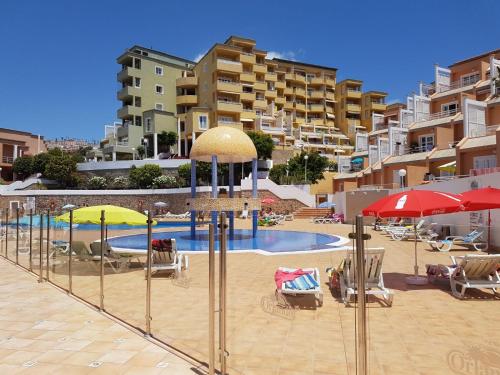 uma piscina com cadeiras e guarda-sóis em frente aos edifícios em Sun and Sea Orlando Apartment with terrace em Adeje