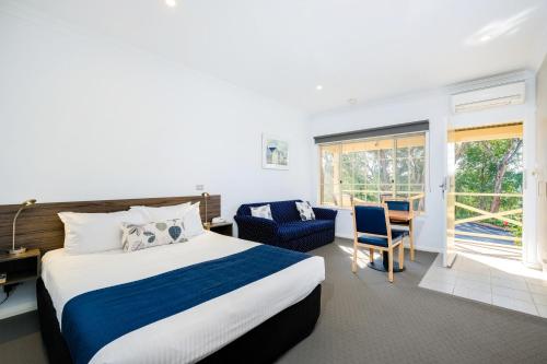 a hotel room with a bed, chair, and a tv at Commercial Golf Resort in Albury