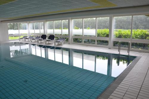 een zwembad in een gebouw met stoelen en water bij Fletcher Hotel - Resort Spaarnwoude in Velsen-Zuid