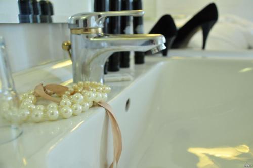una collana di perle seduta su un lavandino accanto a un rubinetto di Hotel Haus Reichert a Baden-Baden