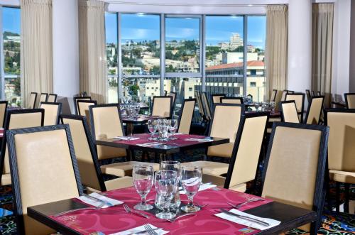 a restaurant with tables and chairs with wine glasses at Golden Crown Old City Hotel in Nazareth