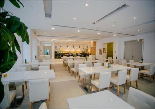 Jinjiang Inn - Changchun Convention & Exhibition Center في تشانغتشون: غرفة طعام مع طاولات بيضاء وكراسي بيضاء