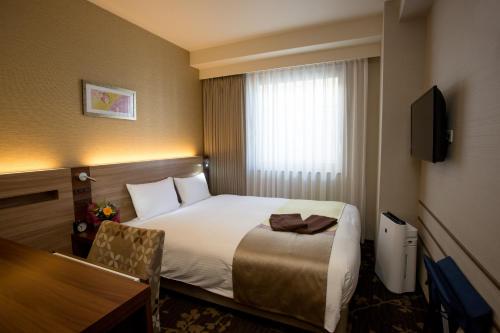 um quarto de hotel com uma cama e uma secretária em Shinsaibashi Grand Hotel Osaka em Osaka