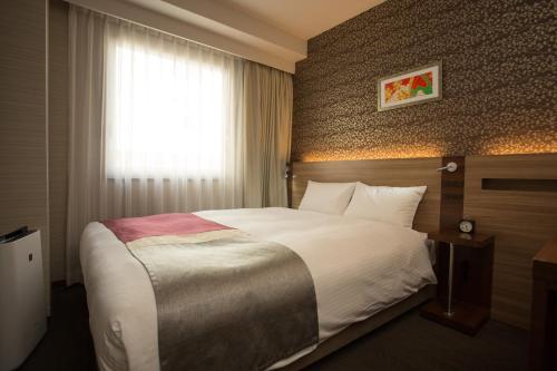 a hotel room with a large bed and a window at Shinsaibashi Grand Hotel Osaka in Osaka