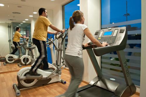 a man and a woman on exercise bikes in a gym at Ibis Budget Lleida in Lleida