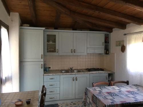 een keuken met witte kasten en een tafel in een kamer bij Casa Mare Tamerici in San Teodoro