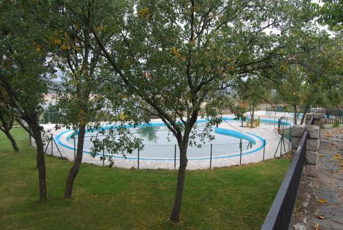 a large swimming pool in a park with trees at Camping de Cervera de Buitrago in Cervera de Buitrago