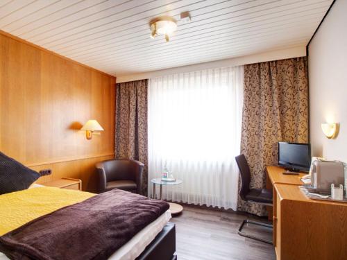 a hotel room with a bed and a desk at Hotel-Restaurant Zum Babbelnit in Mainz