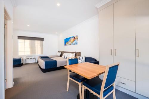 a bedroom with a bed and a table and chairs at Commercial Golf Resort in Albury