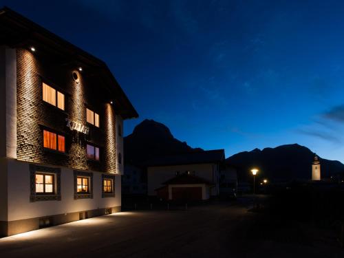 a building at night with a lighthouse in the background at Pension Kilian in Lech am Arlberg