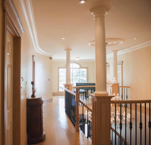 a hallway with a spiral staircase with columns and a stair railing at JstLikeHome - Luxury Mansion & Guesthouse in Ottawa