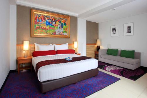 a hotel room with a large bed and a couch at Ivory Hotel Bandung in Bandung