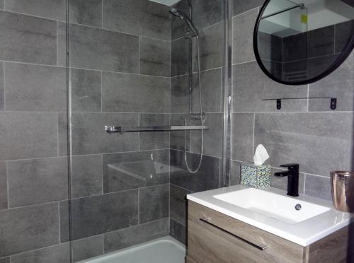 een badkamer met een douche, een wastafel en een spiegel bij Les marinas vue Mer in Deauville