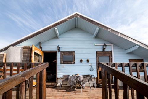 a blue house with a porch with a table and chairs at Healing Hands in Merom Golan