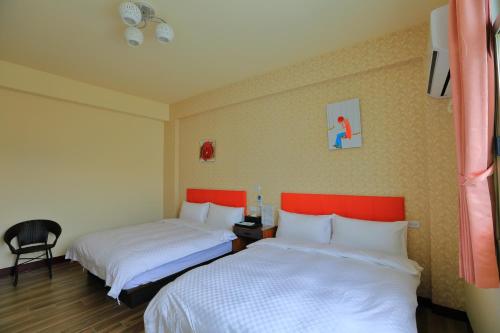 a hotel room with two beds and a chair at Miyama Bed and Breakfasts in Chishang