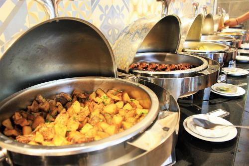 a row of pots filled with food on a table at Fame Hotel Sunset Road in Kuta