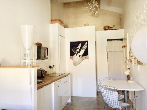 een keuken met witte kasten en een witte tafel bij Mon Refuge Urbain in Montpellier