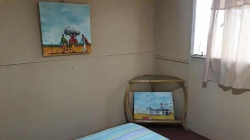 1 dormitorio con espejo y una pintura en la pared en Paljas Backpackers en Potchefstroom