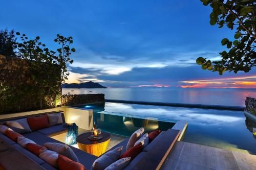 een zwembad met een bank en uitzicht op de oceaan bij U Pattaya in Na Jomtien