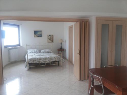 Un dormitorio con una cama y una mesa y una ventana. en Attico Ostuni, en Ostuni