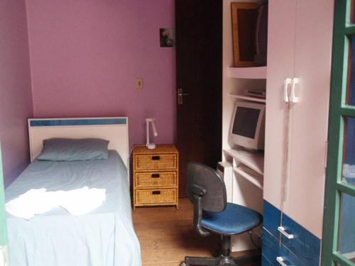 a bedroom with a bed and a chair and a microwave at Hospedagem dos Arvoredos in Ubatuba