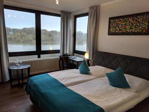 a bedroom with a bed and a large window at Rheinterrassen Hotel Café Restaurant in Widdig
