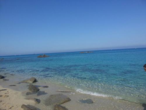 a person standing on a beach near the water at Hotel La Fattoria Sul Mare in Capo Vaticano