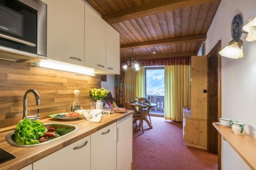 a kitchen with a sink and a counter with vegetables on it at Aparthotel Gallahaus in Zell am Ziller