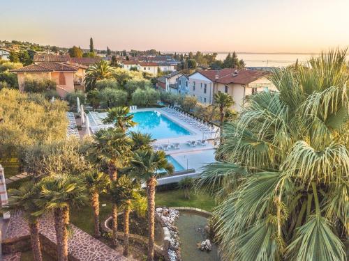 vista aerea di una villa con piscina e palme di Hotel Villa Olivo Resort 3S a Bardolino