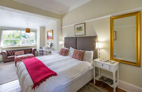 a bedroom with a large bed with a red blanket on it at Brooklands House in Cape Town